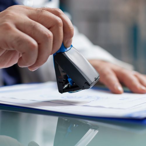 Doctor holding medical stamp to put on prescription paper