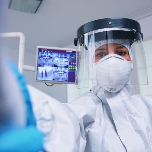 Patient pov of dentist in covid protectiv suit measuring temperature in modern dental office with new normal. Stomatolog wearing safety gear against coronavirus during heatlhcare check of person. SSUCv3H4sIAAAAAAAACoRVy67kNBDdI/EPV15j4Uf8CF/AZsSCJWLhV7rDJHErcQbQ1f13Km8nkxl60WpXHdfjlOv0+48/vL0ha4baoV/e3qcTnOumGYfUm1THDszkp9Xeh86HPrd86bkkuSH4OsW+Nk1utCa5Z2faAMZubJrJ/DE70ZBMGocwZNnb2vVxSNF9fkEZ4KBbHOOjDbMHrExtZt8H0w6pnuMfZsp4X4FF7PddbOLY2/hPHrSFXK9nTPGUytaPpYTJAw6+OYbnmFLob6oIrzjUR6jD84qdFyeLaUz778niTHfKd3jaOI0hNKENXZoC84w+Z1J4AN8nArdx/rGc3zbHmiiBC/0aTJOezvTh508wMwcDWxMuXY52Qv1m/woOkm6eJes3Qv7u6tC5cBfnUz240DSmC3HMoi0//txZecD9iZb3j6zFHlo3ywtZG0KcCM5CxXGohMGFpR5bxuDoCePBCFqUdisDWSZUqKjDjhEA0xBwSQ3BzHHNmTAV9e4AW10KQjk2qrC4KHmFjScOE6K9s5RTGoodTEzlmdcEG0MFLqqixKVSFEtGuCyJdKHyO9iL0hhiLBaV0AD2CuvKKVzBtxQlLV1ZzcwsdKDPf8Mra+exrkSY0dcxG/OXCFO7PohXX7u6e2TXYnrOO7tdc3HsUj/RjPbimhhfxjbT/lQQM2z2pxkGgPvNnr88UIjYZnm6mOYhrVGRh6c5HSmQLCkrgBEldcG1RvnqP2uIM5ezFTi+mmh8mJLur+xGFCQlWkmp2P7ezvqwAJRi205flWIF6CKLsGnGne+kHjf+s5DcAK6acoe5yMsKKWUGuQrNHWaTnDvfJj53vqsMzRhNmGALZBOAabHbGio9T+lmAKUU5P9qP2NuKThDzu2dfecRTgv53fmfAfcjOmO+EmQAUVJIqb9PJGAUKeZlXbVv/w8EYO1zCT8RiQoiueQwqENNLjyiooAtK3h5qNOFRkRB2UpF4YOuf0yIFrBHXG2rmbEIlJlHHBwggTtGCSVE0ayQnFHECDAFm374r4RCL1wKRkuxQ77iE1FJNNP86OXKJtJal7A3elbMlcZ6eouIOu6NDQZ7ySmGvgzWQjCsXKVEUXFpNYFbH/8BAAD//wMAL22cm/oIAAA=
